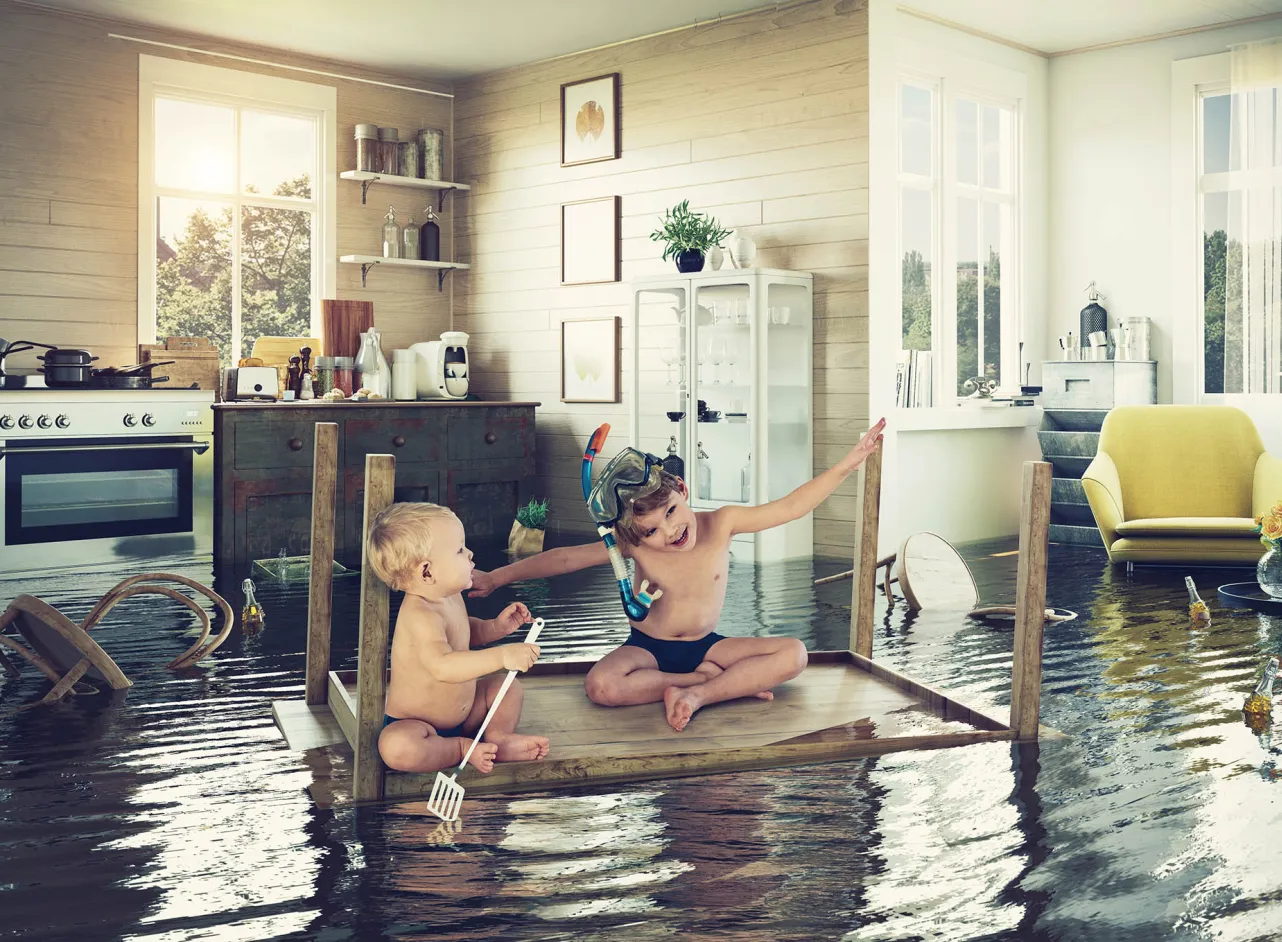 deux enfants sur un radeau de table dans une cuisine inondée
